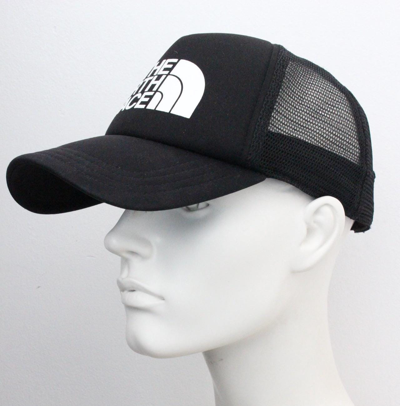 The North Face plain black baseball cap with big white spell out logo. Classic trucker style hat with fully adjustable back