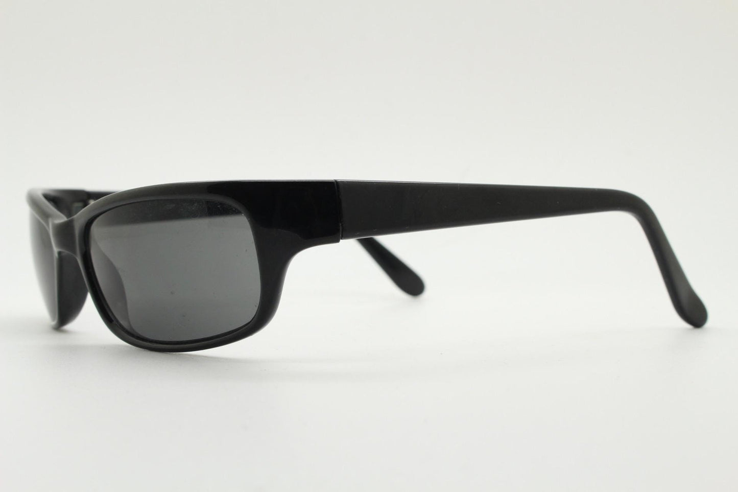 90s vintage curved wraparound sunglasses. Aerodynamic low profile plain black gloss curved cat eye frame. Minimal shield design. NOS