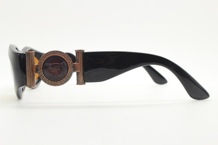 90s vintage oval sunglasses. Low profile black gloss frame with massive bronze metal arm crests and brown lenses. BNWT. Unworn NOS