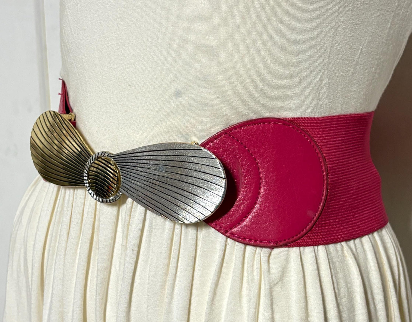 80s vintage womens tall pink elastic belt. Large winged silver and gold buckle. Flattering cinch effect. Adjustable stretchy size range