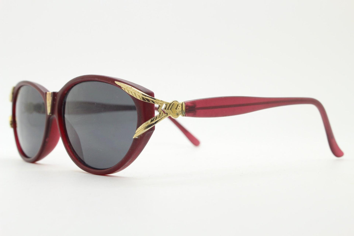 80s vintage Revlon cat eye sunglasses. Women's dark pink transparent frosted frame with golden Y fork ornate temples. 90s cateye. NOS