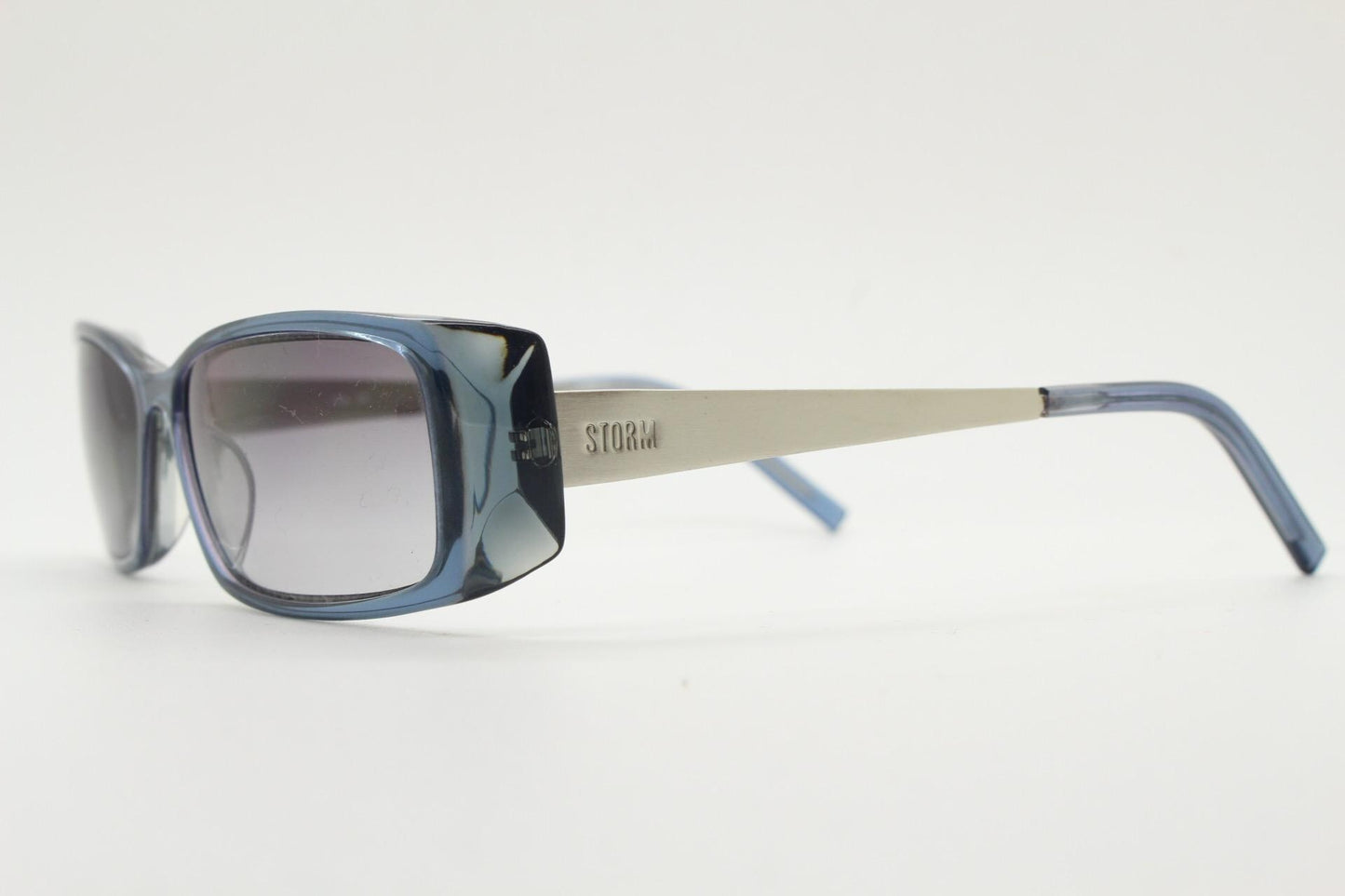 90s vintage rectangular low profile sunglasses by Storm. Transparent grey acetate front with brushed steel arms. NOS. 2000s