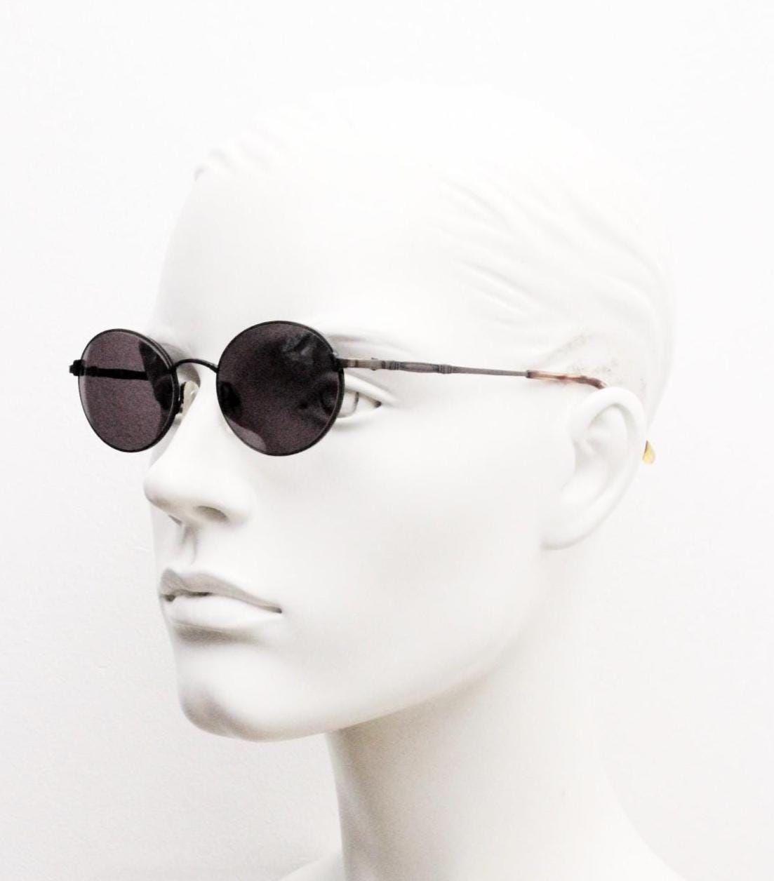 90s oval vintage solid metal sunglasses by Sunex. Minimal gloss finish bronze brown frame with grey lenses and subtle arm detail. Unused NOS