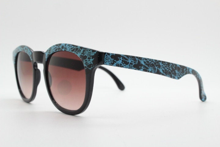 80s vintage rounded wayfarer design sunglasses. Abstract patterned blue brow and arms on a black frame with graduating  lenses. Unused NOS