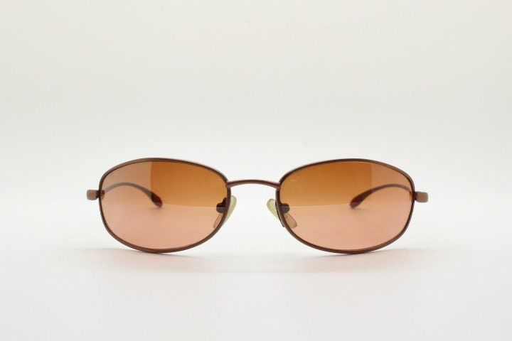 Y2K vintage oval small bug eye sunglasses. Curved copper satin finish metal frame with slender arms. Unused 2000s NOS