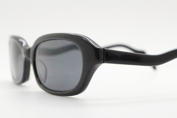 90s vintage rectangular minimal cat eye sunglasses. Small black acetate low profile frame with extraordinary waved arms. Unused NOS