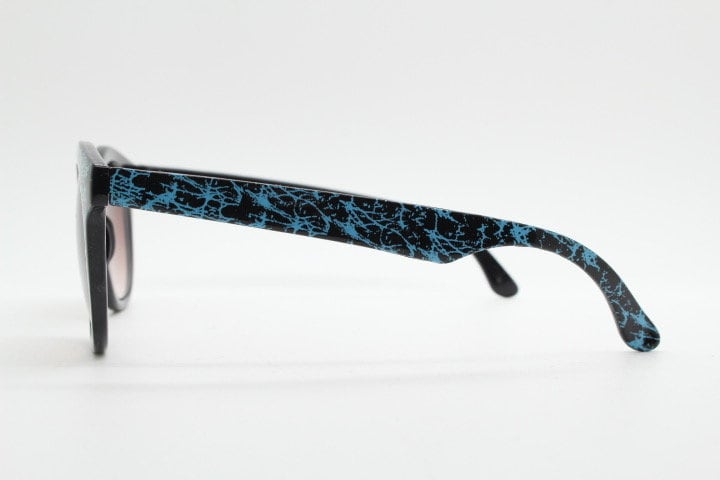 80s vintage rounded wayfarer design sunglasses. Abstract patterned blue brow and arms on a black frame with graduating  lenses. Unused NOS
