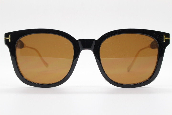 Tom Ford vintage wayfarer design sunglasses made in Italy. Slightly cat eye form in plain black gloss acetate with gold arms