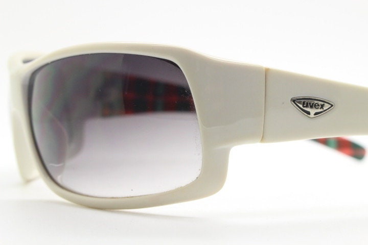 Uvex Y2k vintage wrap around bug eye sunglasses. Curving white sports shield frame with black lenses and tartan interior. Rave 2000s. NOS