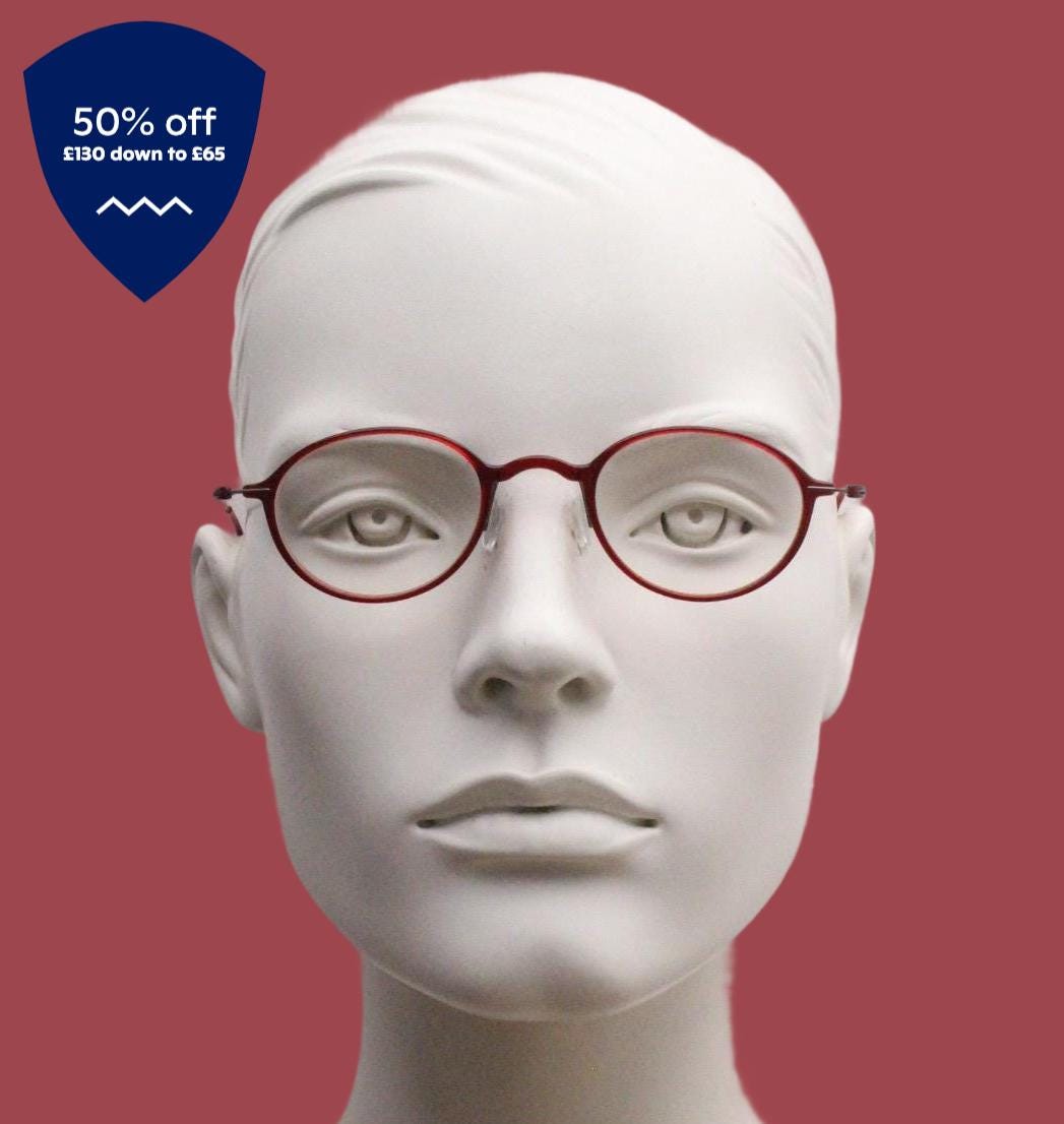 A white mannequin head wearing red-tinted glasses against a red background.