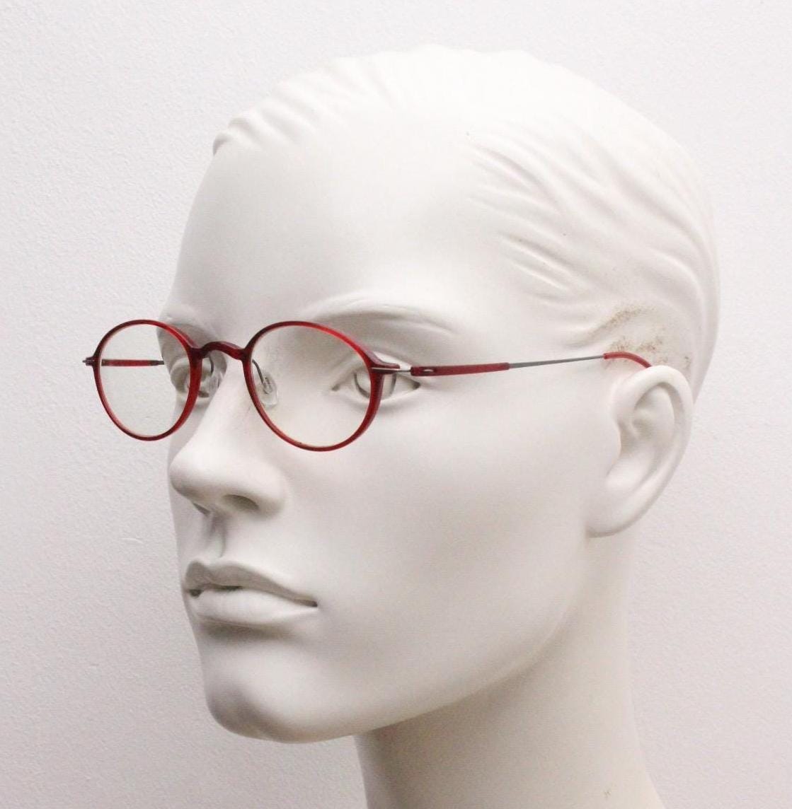 A mannequin head wearing red-framed glasses against a white background.