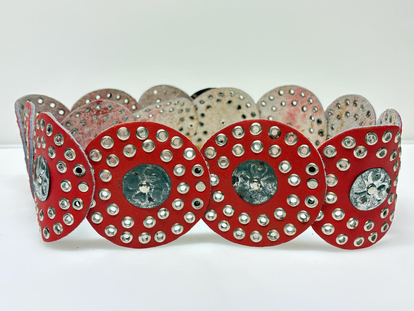 80s vintage womens huge red leather circles belt. Versatile statement piece with holed studs, metal discs and big 'shield' buckle. NOS