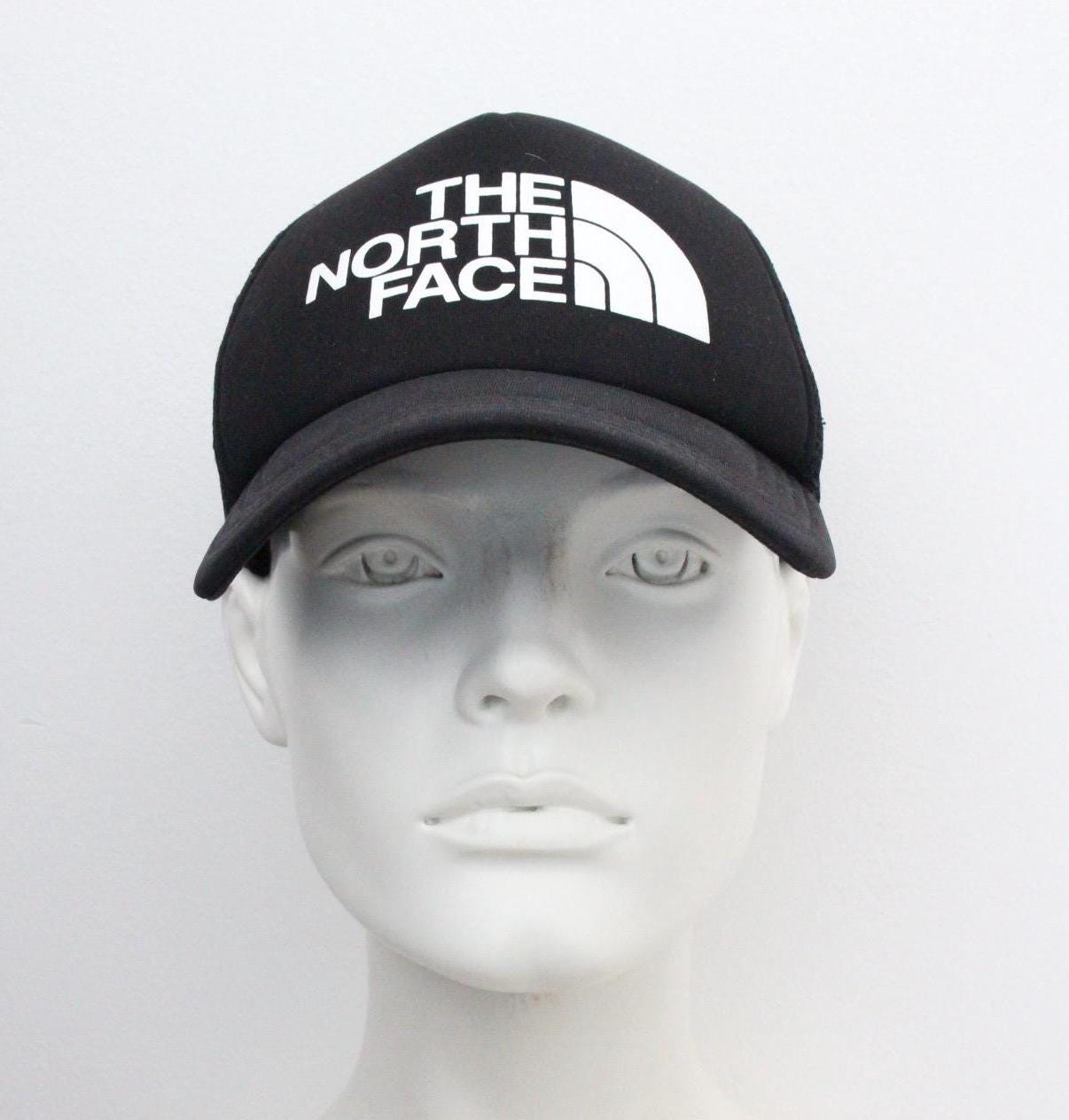 The North Face plain black baseball cap with big white spell out logo. Classic trucker style hat with fully adjustable back
