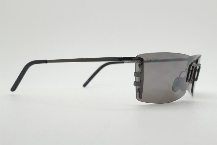Y2K vintage wraparound sunglasses. Dynamic frameless shield design in gunmetal grey with slight mirror glaze rectangular lenses. 2000's NOS