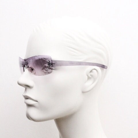 Y2K vintage visor sunglasses. Frameless 2000's purple wraparound mini mask shield design with light tone mono lens and flower print. 00s NOS