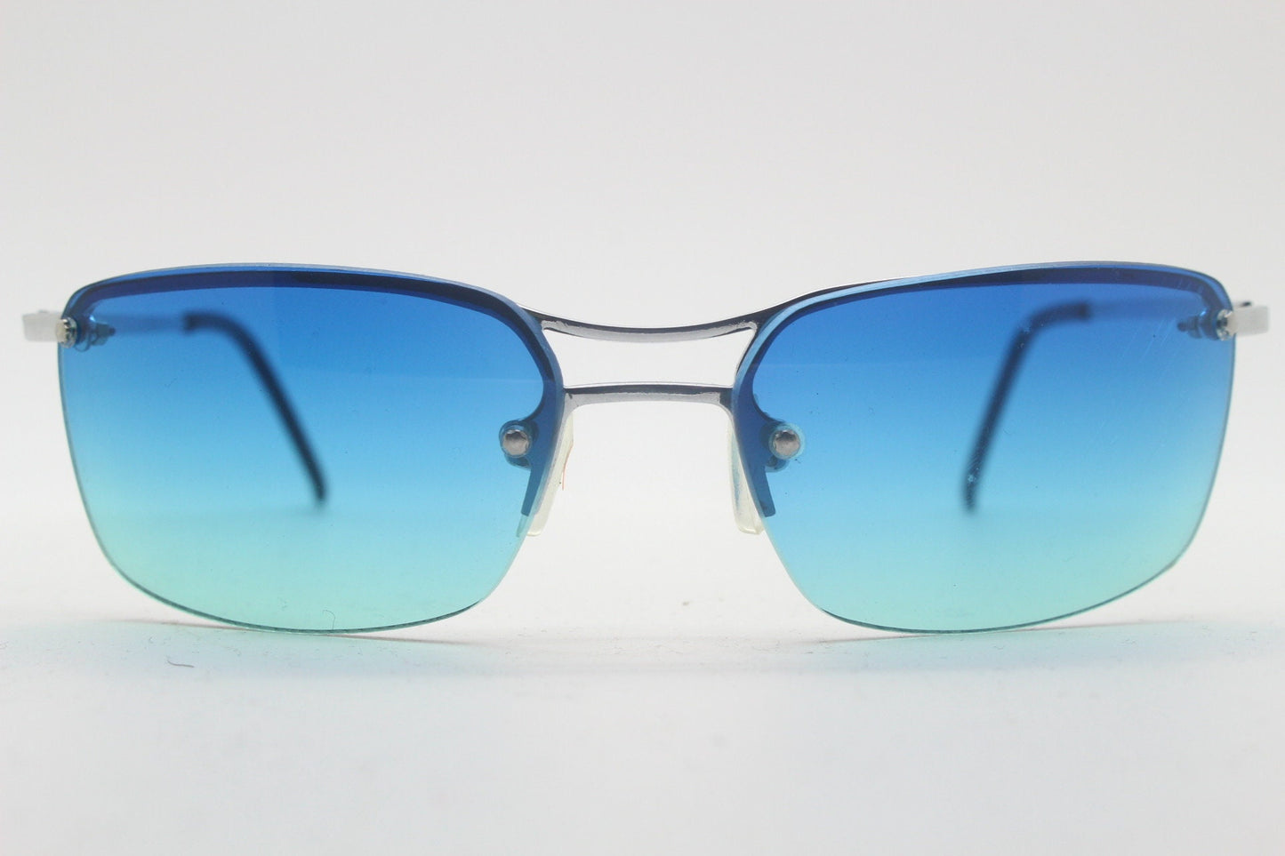 Y2K vintage visor sunglasses. Half frame wraparound shield design with light tone graduating turquoise to aquamarine lens. 2000's. 90s. NOS