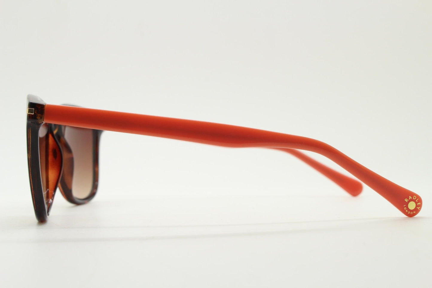 Modified wayfarer design sunglasses by Radley. Tortoise front with bright orange arms and Havana brown lenses. Vintage. Unused NOS