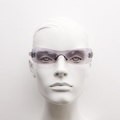 Y2K vintage visor sunglasses. Frameless 2000's purple wraparound mini mask shield design with light tone mono lens and flower print. 00s NOS