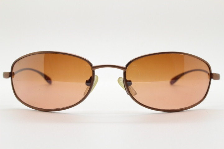 Y2K vintage oval small bug eye sunglasses. Curved copper satin finish metal frame with slender arms. Unused 2000s NOS