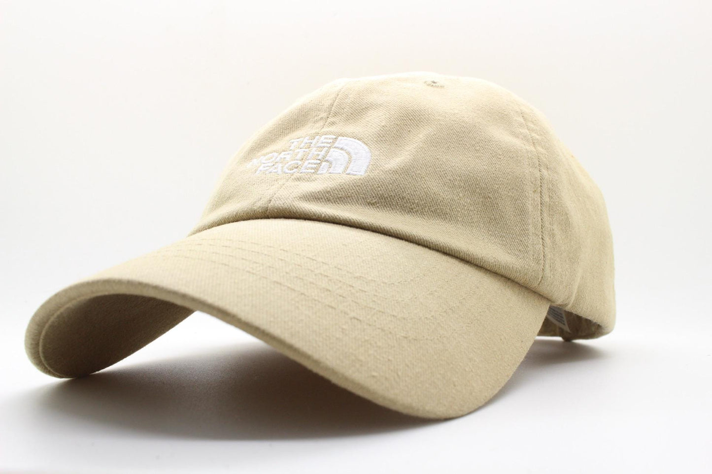 The North Face beige / sand colour baseball cap with white spell out logo. Classic trucker style hat with fully adjustable back. One size