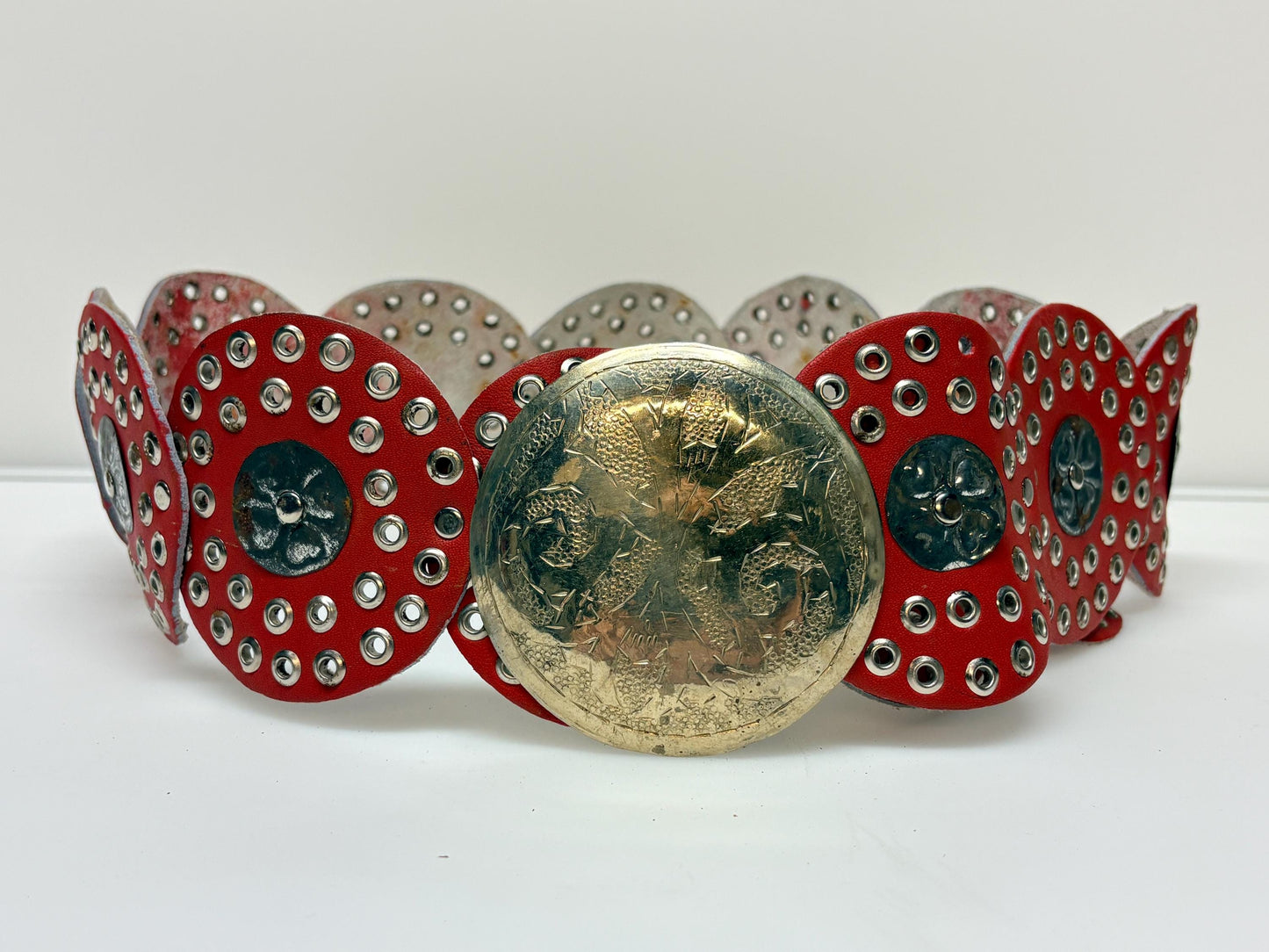 80s vintage womens huge red leather circles belt. Versatile statement piece with holed studs, metal discs and big 'shield' buckle. NOS