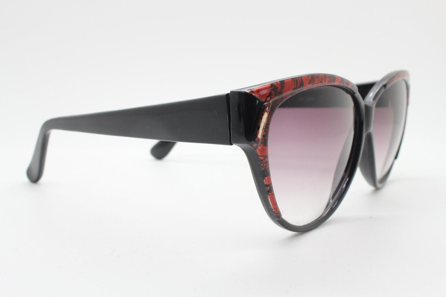 80s vintage oversized cateye sunglasses. Women's black cat eye frame with red patterned brow and sizzling gradient lenses