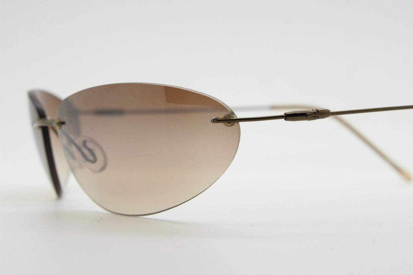 90s vintage frameless oval wraparound sunglasses. Minimal curved almond shaped lenses with brown chrome arms. 2000s NOS. Matrix cosplay