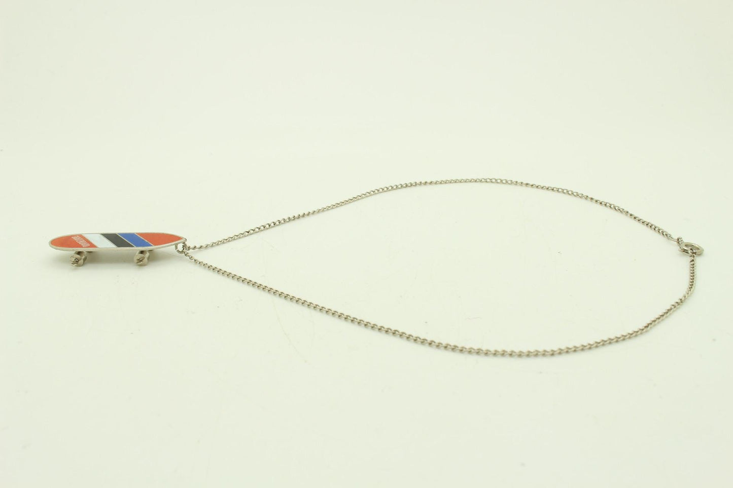 80s vintage skateboard pendant necklace. Metal chrome with enamelled red, blue and white colour stripes. Charming authentic design. NOS