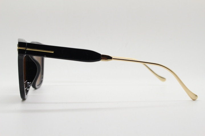 Tom Ford vintage wayfarer design sunglasses made in Italy. Slightly cat eye form in plain black gloss acetate with gold arms