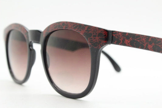 80s vintage rounded wayfarer design sunglasses. Abstract patterned red brow and arms on a black frame with graduating  lenses. Unused NOS