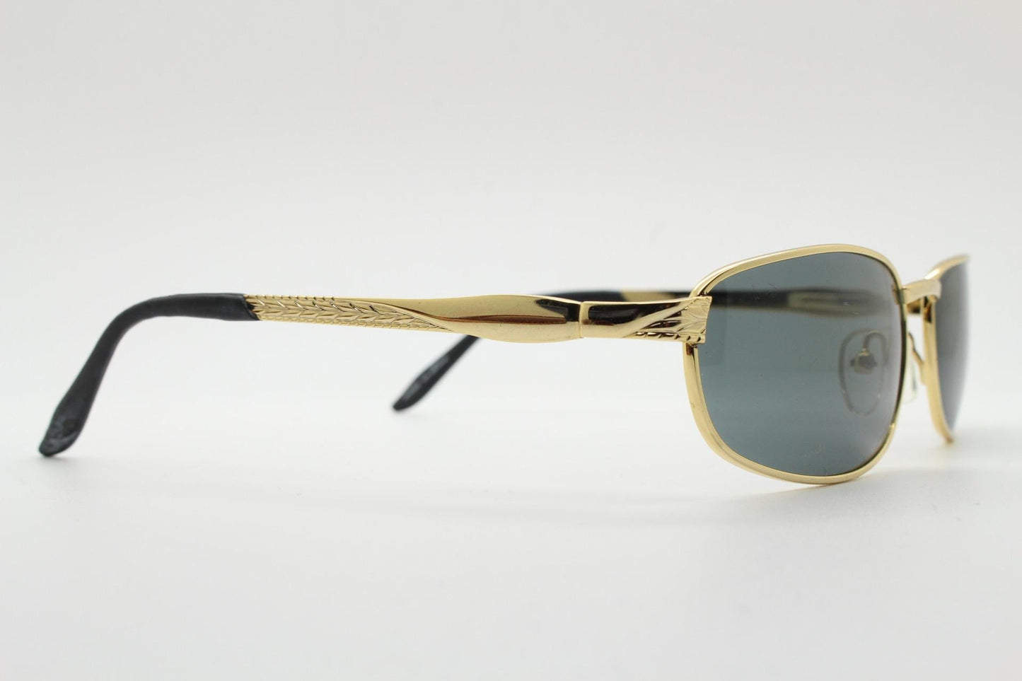 90s vintage low profile gold rectangular sunglasses. Solid metal frame in a shiny chrome finish embossed arm pattern and green lenses. NOS