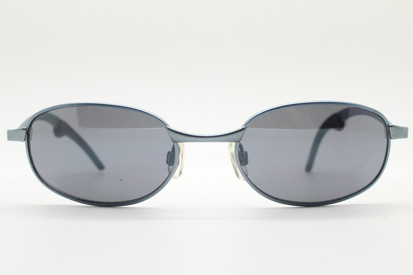 90s vintage oval small bug eye sunglasses. Curved blue satin finish solid metal frame with stylised arched arms and rubber ends. Unused NOS