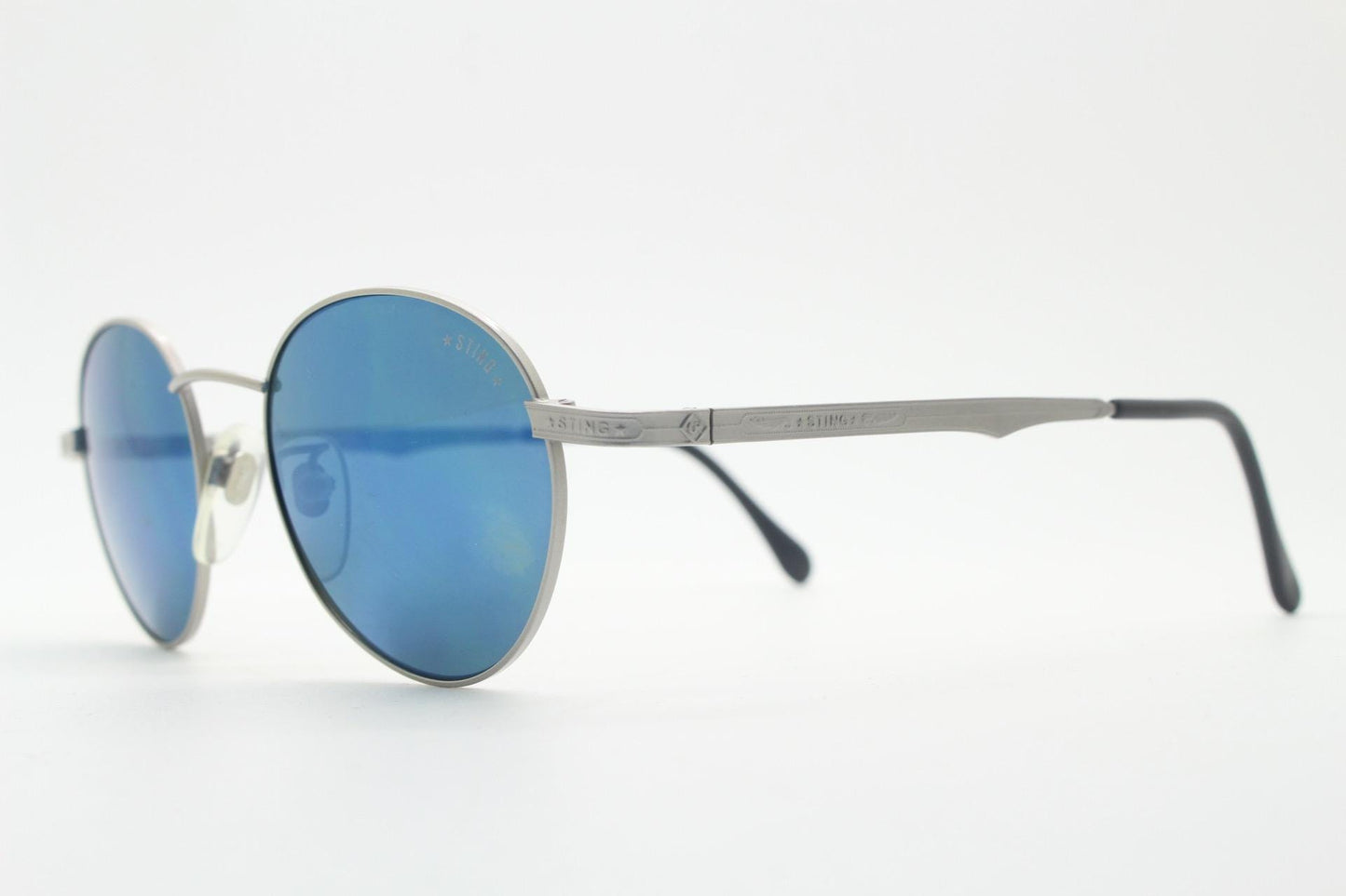 Sting 90s vintage oval sunglasses made in Italy. Minimal grey aluminium look in slightly small proportions with blue mirror lenses