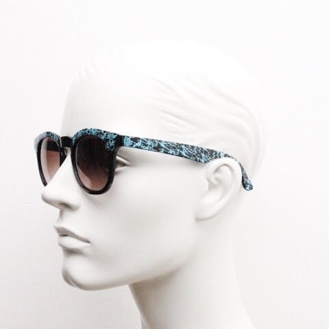 80s vintage rounded wayfarer design sunglasses. Abstract patterned blue brow and arms on a black frame with graduating  lenses. Unused NOS