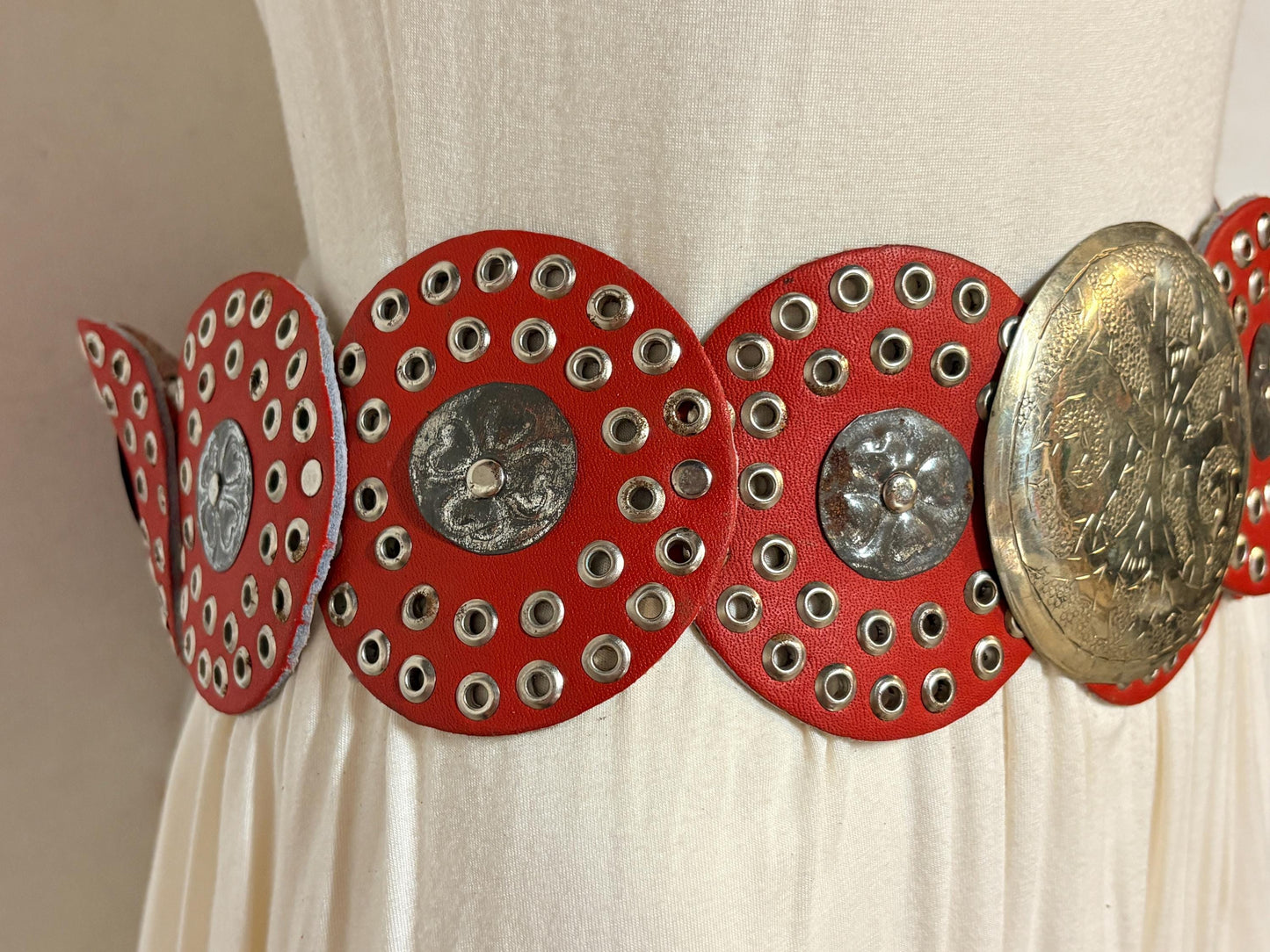 80s vintage womens huge red leather circles belt. Versatile statement piece with holed studs, metal discs and big 'shield' buckle. NOS