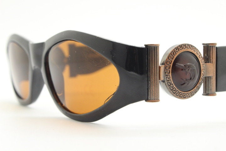 90s vintage oval sunglasses. Low profile black gloss frame with massive bronze metal arm crests and brown lenses. BNWT. Unworn NOS