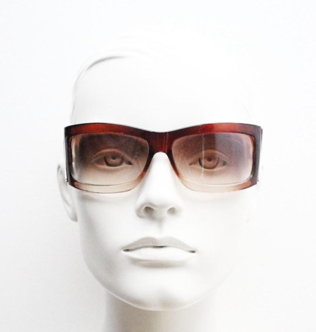 Y2K vintage big wrap around sunglasses. Transparent brown shield design with hot graduating lenses and big X crest. 2000s bug eye. NOS