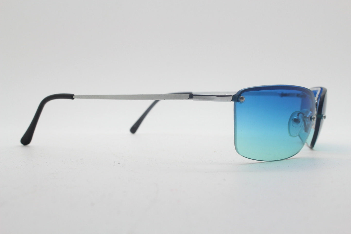 Y2K vintage visor sunglasses. Half frame wraparound shield design with light tone graduating turquoise to aquamarine lens. 2000's. 90s. NOS
