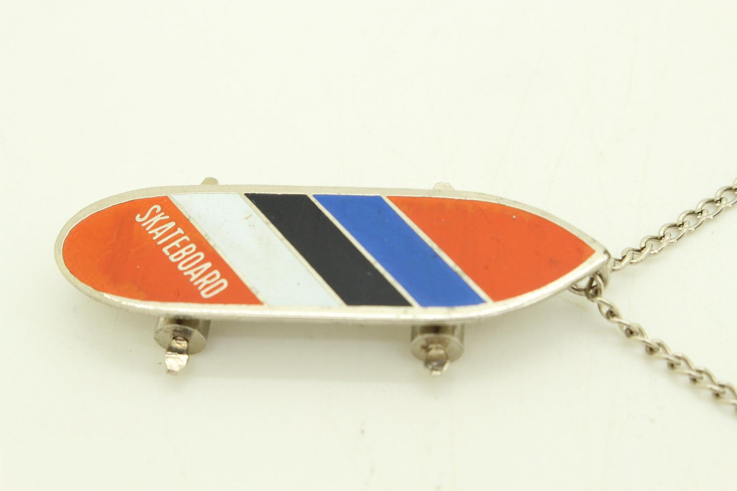 80s vintage skateboard pendant necklace. Metal chrome with enamelled red, blue and white colour stripes. Charming authentic design. NOS