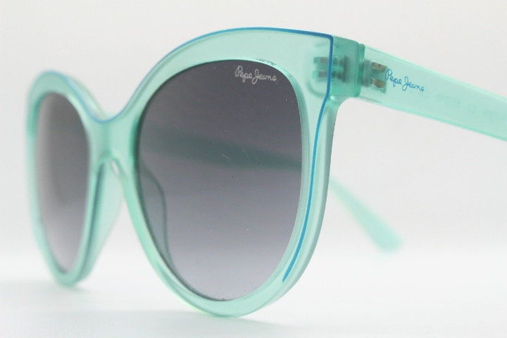 Pepe Jeans big cat eye sunglasses. Transparent chunky aquamarine frame with contrasting black graduating lenses. Womens vintage cateye