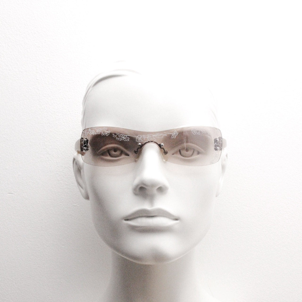 Y2K vintage visor sunglasses. Frameless 2000's wraparound mini mask shield design with light tone mono lens and flower print. 00s NOS