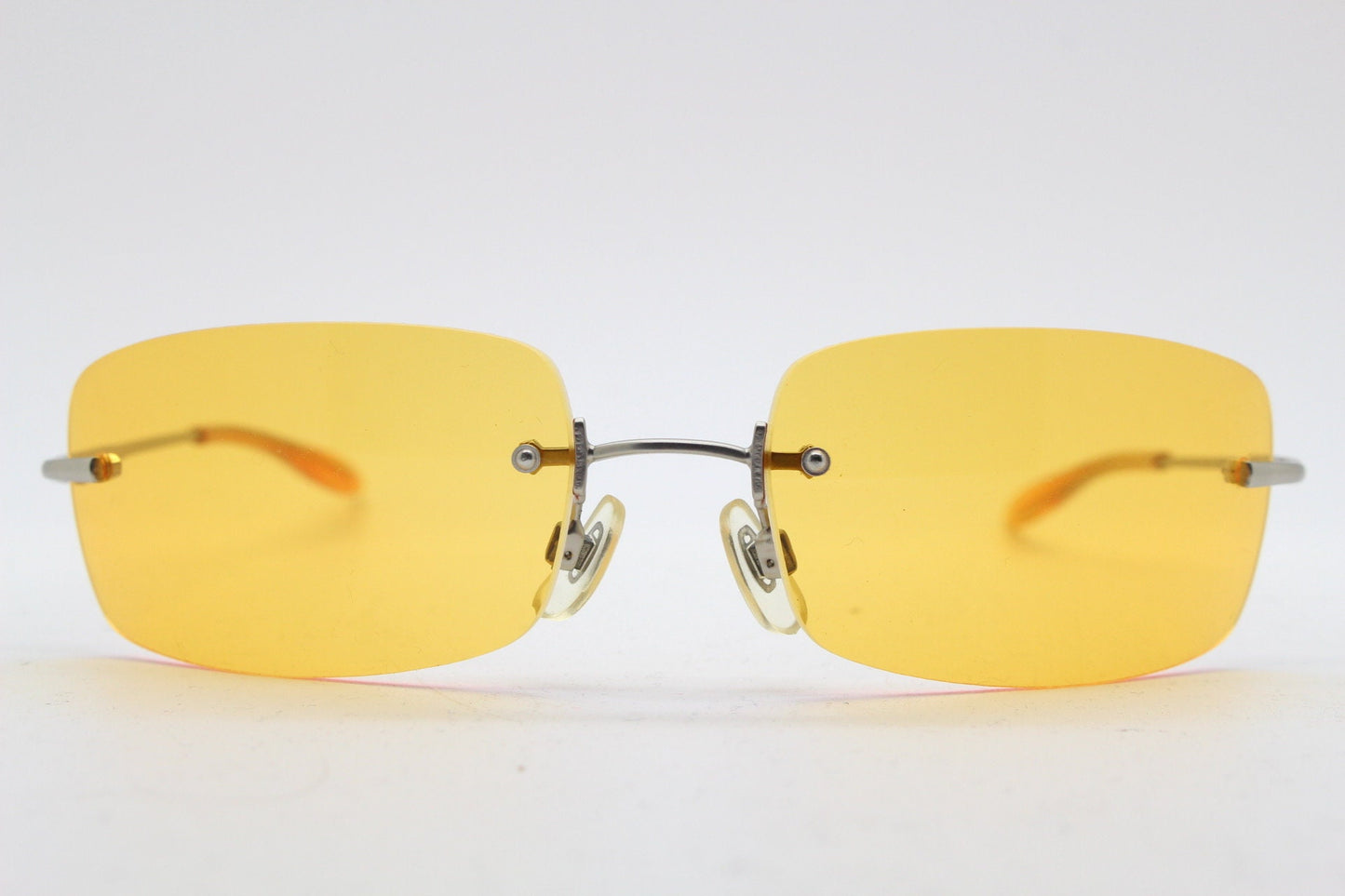 Y2K vintage frameless orange sunglasses. Rectangular wrap around lenses with satin silver bridge and arms. 2000s club kids. 00's. 90s. NOS