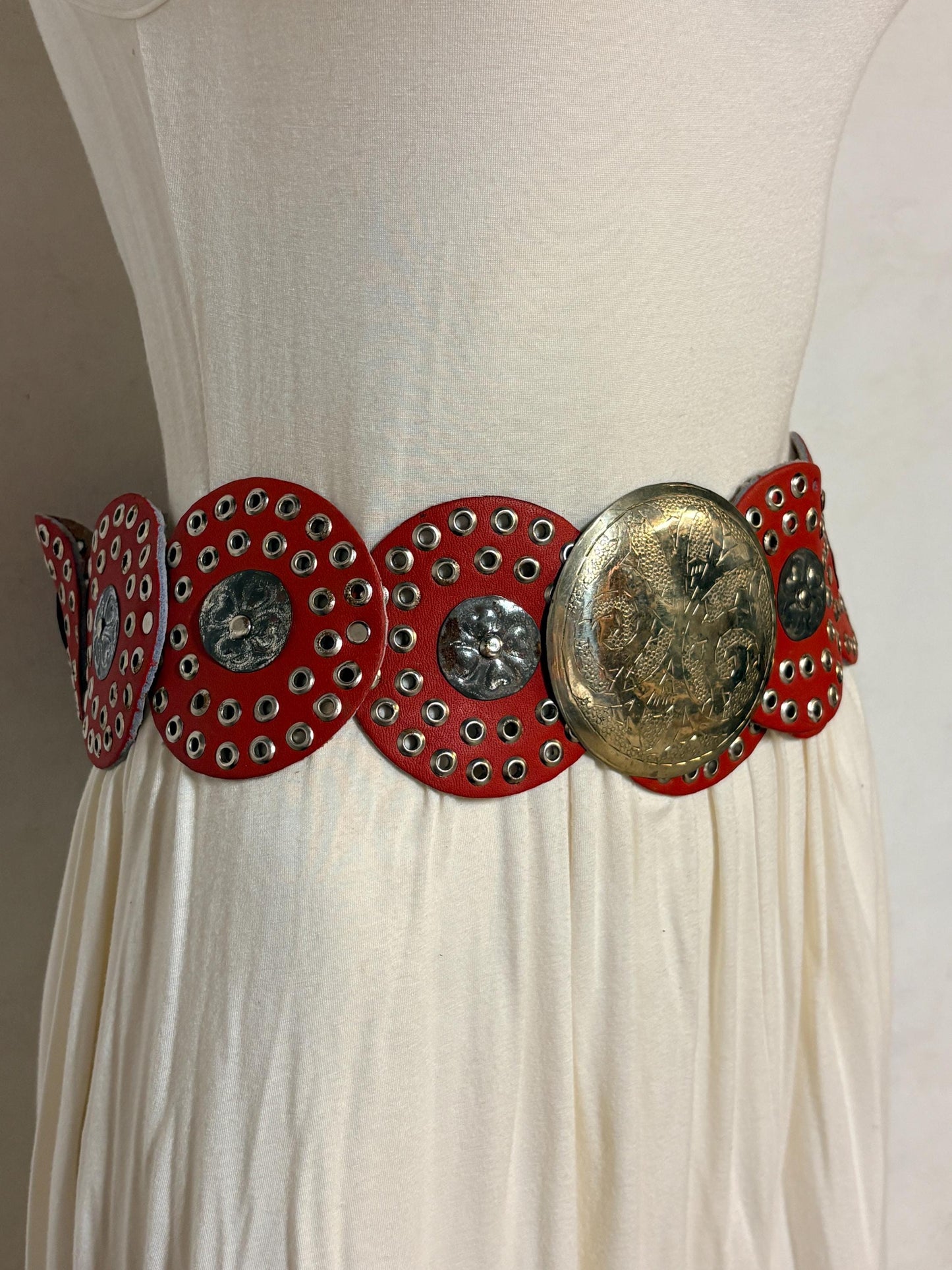 80s vintage womens huge red leather circles belt. Versatile statement piece with holed studs, metal discs and big 'shield' buckle. NOS