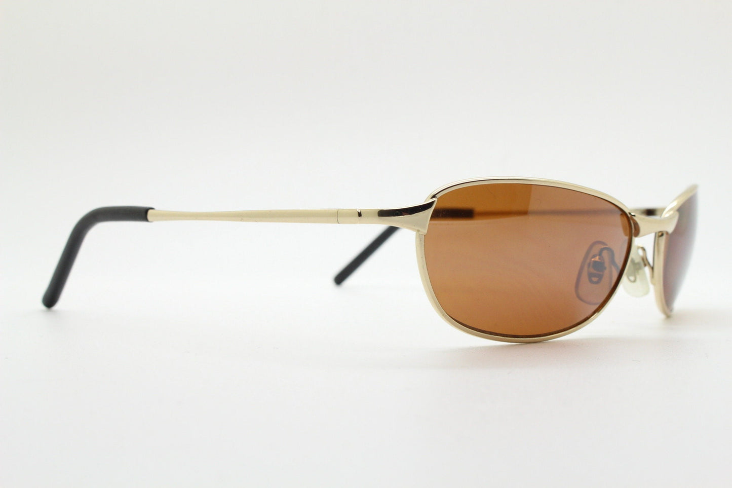 90s vintage curved angular oval sunglasses. Solid metal small bug eye frame in gold chrome with mid tone brown lenses. 2000's. Y2K NOS