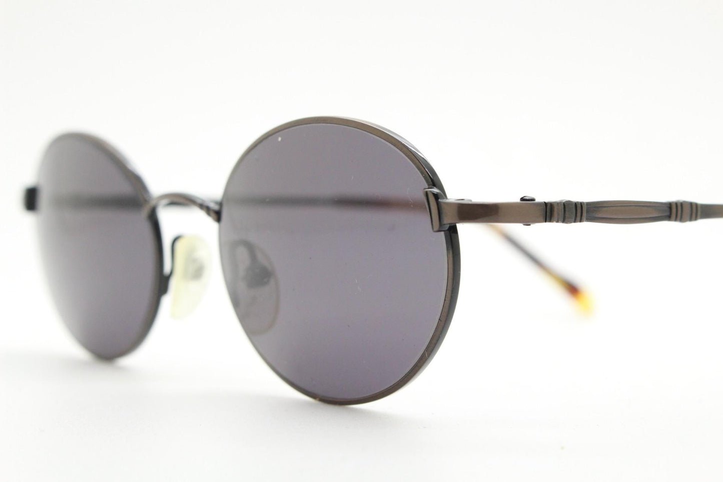 90s oval vintage solid metal sunglasses by Sunex. Minimal gloss finish bronze brown frame with grey lenses and subtle arm detail. Unused NOS