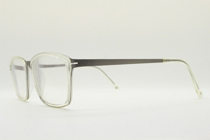 Modo rectangular eye glasses made in Japan. Matt grey titanium optical frame encasing transparent crystal acetate front. Prescription RX