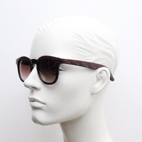 80s vintage rounded wayfarer design sunglasses. Abstract patterned red brow and arms on a black frame with graduating  lenses. Unused NOS