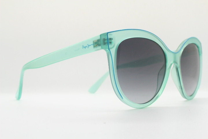 Pepe Jeans big cat eye sunglasses. Transparent chunky aquamarine frame with contrasting black graduating lenses. Womens vintage cateye