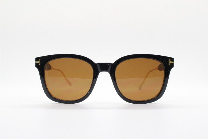Tom Ford vintage wayfarer design sunglasses made in Italy. Slightly cat eye form in plain black gloss acetate with gold arms