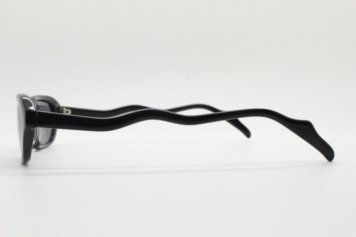 90s vintage rectangular minimal cat eye sunglasses. Small black acetate low profile frame with extraordinary waved arms. Unused NOS
